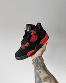 Jordan 4 Red Thunder CT8527-016 in hand vastgehouden bij het hielstuk met zichtbare hieltab, suède afwerking en iconische Thunder-accenten