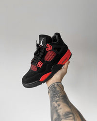 Jordan 4 Red Thunder CT8527-016 in hand vastgehouden bij het hielstuk met zichtbare hieltab, suède afwerking en iconische Thunder-accenten