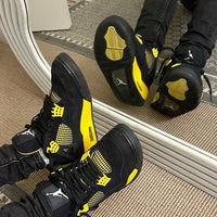 Air Jordan 4 Thunder 2023 DH6927-017 gedragen met losvallende jeans, zichtbaar in beweging met felgele middenzool en zwarte cages