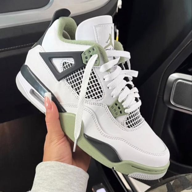 Air Jordan 4 Seafoam AQ9129-103 in hand vastgehouden bij de hiel, met zicht op mintgroene heeltab, witte lederen upper en zachte binnenzijde