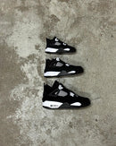 Meerdere paren FQ8138-001 strak gestyled op matzwarte ondergrond, met white-on-black colorblocking en zichtbare tonglabels in beeld