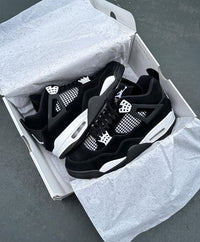 FQ8138-001 net uit de doos gehaald met zicht op witte details, gelaagde midsole en de originele doos met cement-print onder het licht