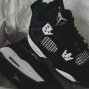 Jordan 4 White Thunder FQ8138-001 gedragen met zwarte cargos en witte sokken, gefotografeerd tijdens lopen met scherpe focus op het silhouet