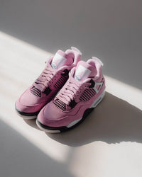Detailopname van AQ9129-501 met focus op het gestikte roze Jumpman-logo en het gespikkelde hielvlak in lavendelgrijze tint