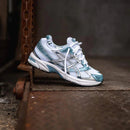 ASICS GEL-1130 Shark Tank 1201A256-116 in hand met dark grey colorblocking, glanzende accenten en lichtgewicht retro-ontwerp

