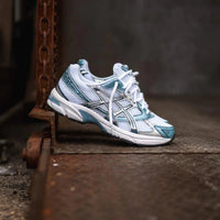 ASICS GEL-1130 Shark Tank 1201A256-116 in hand met dark grey colorblocking, glanzende accenten en lichtgewicht retro-ontwerp

