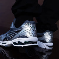 Sneaker gedragen in een casual streetwear look – ASICS Jasper Green edition in combinatie met wijde broek en witte sokken

