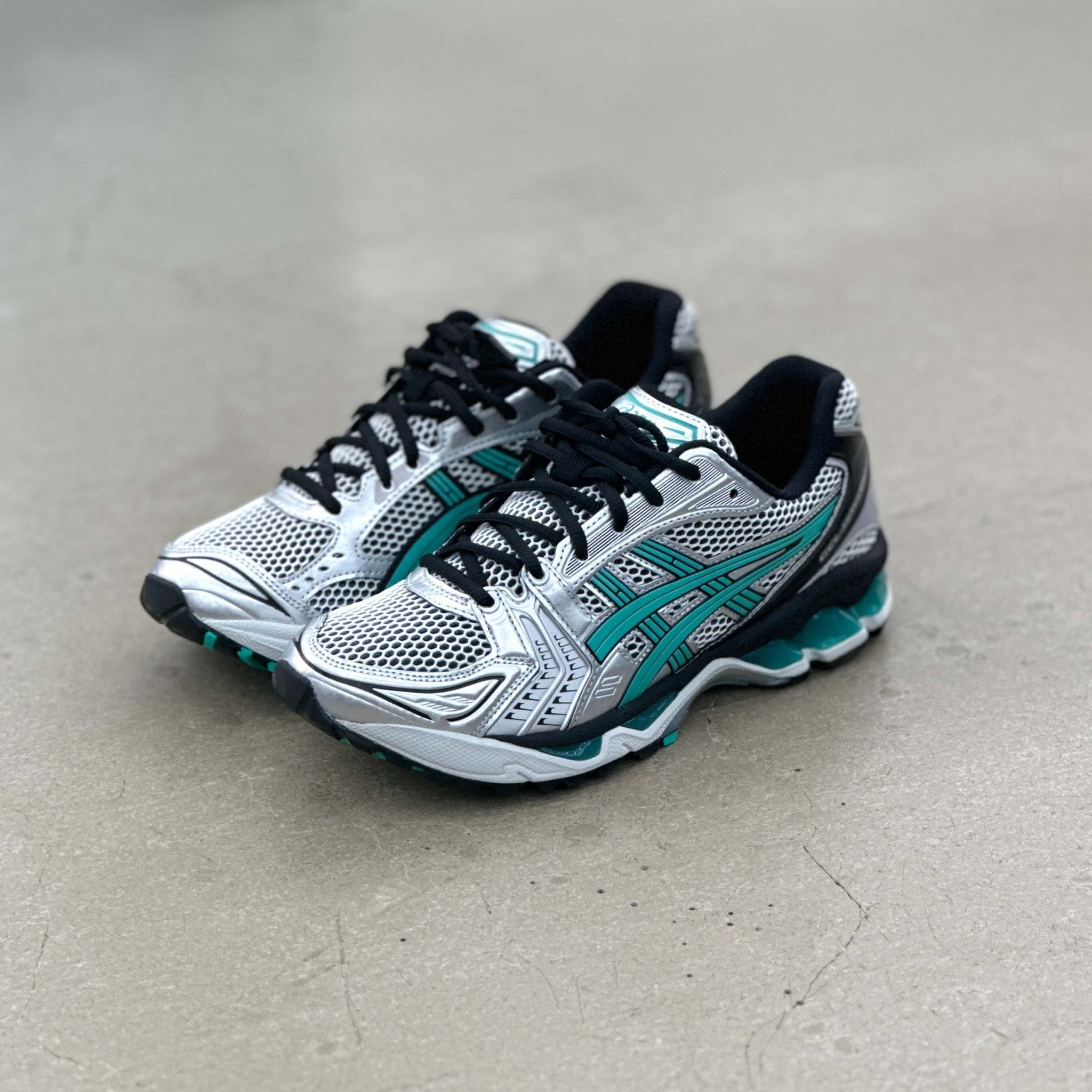 ASICS Tiffany sneaker vastgehouden met zicht op textuur van het bovenwerk, zilvergrijze lijnen en reflecterende structuur

