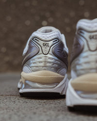 In-hand shot van Kayano 14 White Graphite Grey – lichtgewicht mesh body, zilvergrijze accenten en GEL-technologie in de zool