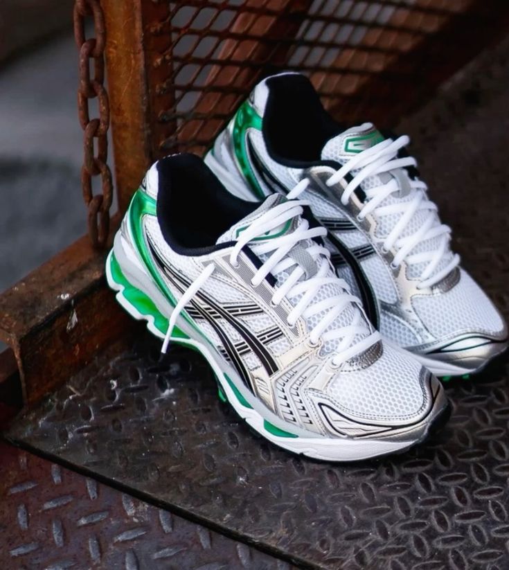 ASICS Gel Kayano 14 White Malachite Green vastgehouden in daglicht met zicht op hielstructuur en reflecterend bovenwerk

