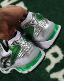 Close-up van de ASICS Gel Kayano 14 White Malachite Green op straat – GEL-technologie en groene details zichtbaar

