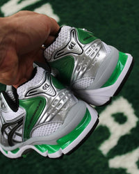 Close-up van de ASICS Gel Kayano 14 White Malachite Green op straat – GEL-technologie en groene details zichtbaar

