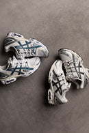 ASICS GEL-Nimbus 9 White Light Indigo 1202A278-108 in hand met metallic indigo accenten, witte basis en retro performance vibe

