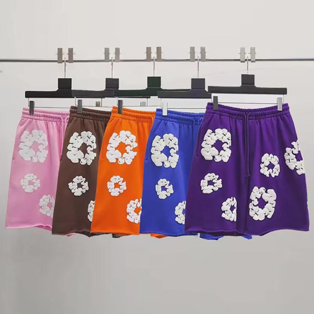 Denim Tears The Cotton Wreath Shorts – reeks hangende shorts in roze, bruin, oranje, blauw en paars met wit Cotton Wreath-borduursel op zachte katoen