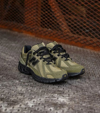 Close-up van het bovenwerk van de 1906R Camo Olive met mesh en camouflageprint. De technische details en gelaagde structuur benadrukken het militaire en functionele karakter van deze uitvoering.

