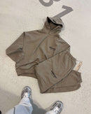 FFear of God Essentials FW24 Light Heather sweatpants flat lay showing elastic cuffs, Essentials branding and beige drawcords. In-hand view of Fear of God Essentials FW24 Light Heather set showing soft cotton texture and relaxed streetwear style.