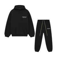 Flatlay van de volledige Fear of God Essentials FW24 set in zwart met wit logo, bestaande uit hoodie en sweatpants tegen witte achtergrond