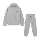 Flatlay van de volledige Fear of God Essentials FW24 set in Light Heather grijs, bestaande uit hoodie en sweatpants, gefotografeerd tegen witte achtergrond