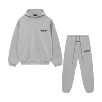 Flatlay van de volledige Fear of God Essentials FW24 set in Light Heather grijs, bestaande uit hoodie en sweatpants, gefotografeerd tegen witte achtergrond