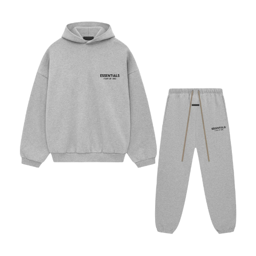 Flatlay van de volledige Fear of God Essentials FW24 set in Light Heather grijs, bestaande uit hoodie en sweatpants, gefotografeerd tegen witte achtergrond