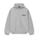 Achteraanzicht van de hoodie in Light Heather met zwarte Essentials-opdruk op de rug, oversized silhouet zichtbaar