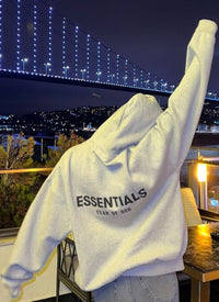 Fear of God Essentials Dark Oatmeal Hoodie – achterkant gedragen bij stedelijke nachtverlichting met oversized fit