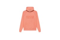 Fear of God Essentials FW22 Coral Hoodie flat lay showing vibrant coral tone, soft cotton fleece and minimalist Essentials chest logo.