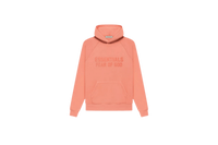 Fear of God Essentials FW22 Coral Hoodie flat lay showing vibrant coral tone, soft cotton fleece and minimalist Essentials chest logo.