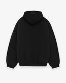 Model wearing Fear of God Essentials FW24 Black Yellow State Hoodie highlighting oversized silhouette, yellow chest lettering and cozy fleece texture.