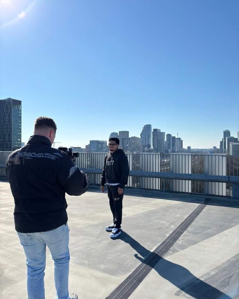 Fear of God Essentials IRON 1977 Full Set gedragen in een stedelijke omgeving met skyline op de achtergrond