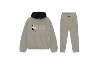 Fear of God Essentials NBA Warm Heather Full Set met hoodie en joggers in warme heathergrijze tint, voorzien van NBA Essentials-logo en contrasterende zwarte capuchon voor een moderne sportieve uitstraling