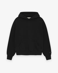 Model wearing Fear of God Essentials SS25 Jet Black Hoodie highlighting oversized fit, tonal logo print and clean modern streetwear style.