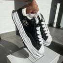 Maison Mihara Yasuhiro Blakey OG Sole Canvas Low Black Maison Mihara Yasuhiro Blakey OG Sole Canvas Low Black – close-up van grove canvas textuur, contrasterende witte stiksels en vervormde shell-toe