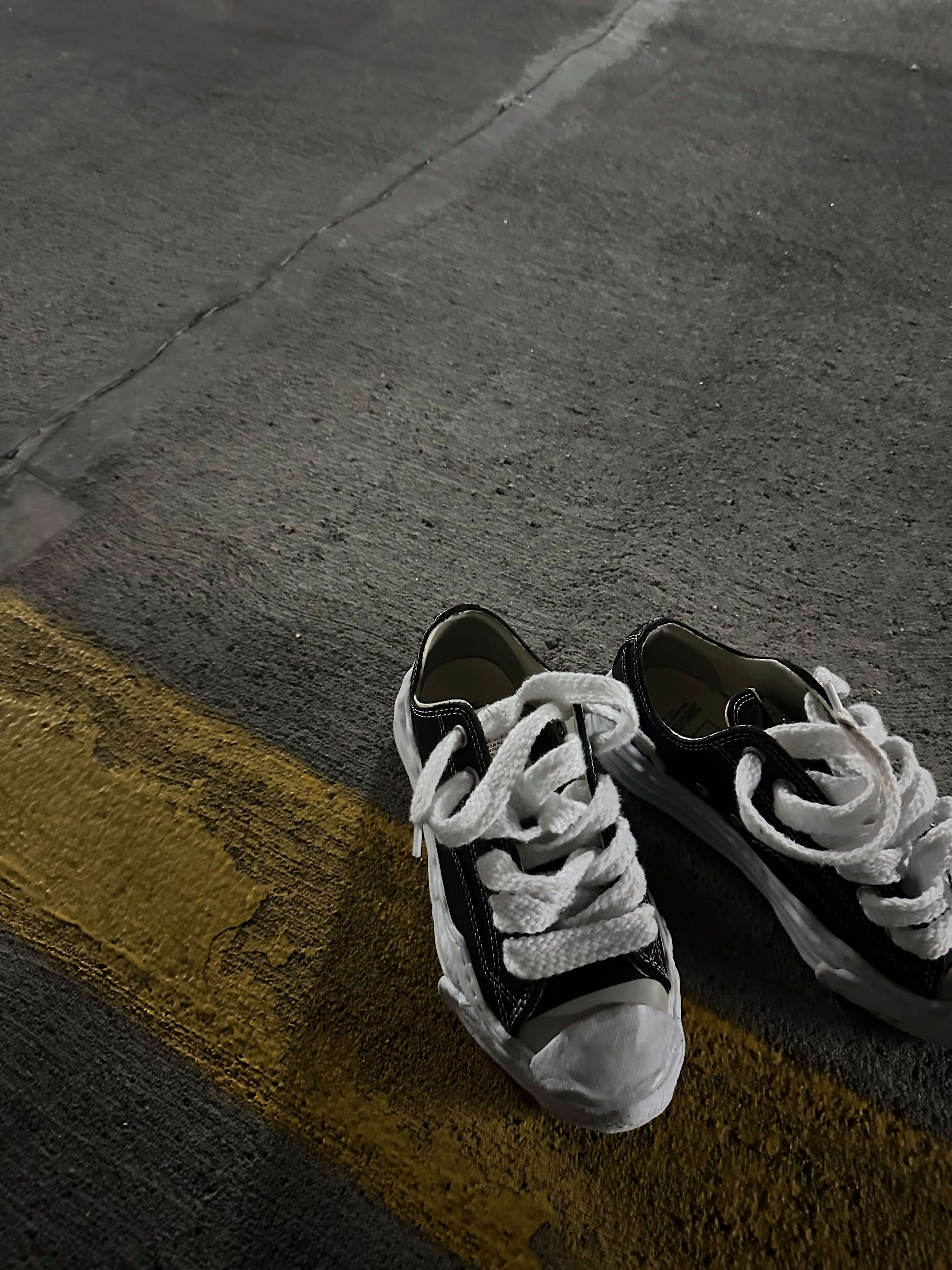 A01FW705 BLK MHY-HANK-OG-BLK Maison Mihara Yasuhiro Hank OG Sole Canvas Low Black – model draagt deze Regular fit sneaker met tapered zwarte denim voor een avant-garde streetlook