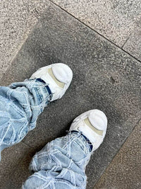 MHY-HANK-OG-WHT Maison Mihara Yasuhiro Hank OG Sole Canvas Low White – model draagt Regular fit met tapered jeans voor een avant-garde streetwear look