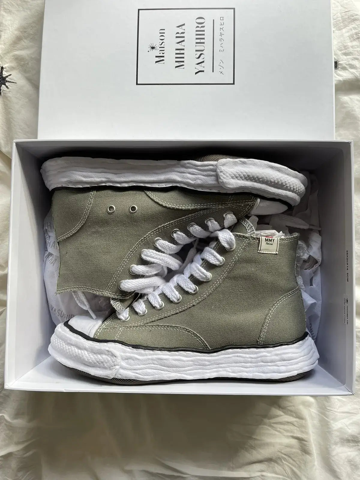 A11FW701-GRN Maison Mihara Yasuhiro Peterson 23 OG Sole Canvas High Green – model draagt de high-top canvas sneaker met tapered denim voor een avant-garde streetwear look 