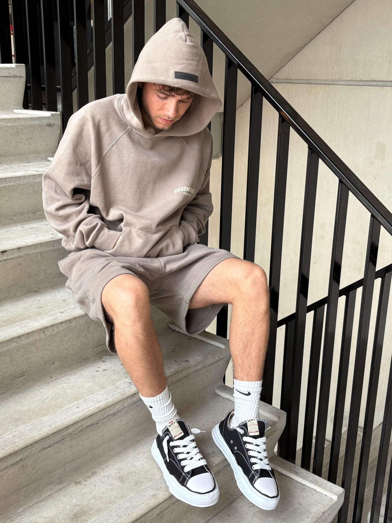 Jonge man zit op trap met Mihara OG Sole Low Black sneakers aan, rauwe streetstyle vibe