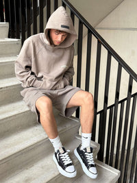 Jonge man zit op trap met Mihara OG Sole Low Black sneakers aan, rauwe streetstyle vibe