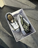 Maison Mihara OG Sole Low Khaki in open doos op stoep, natuurlijke schaduwen benadrukken het ruwe canvas en dikke zool