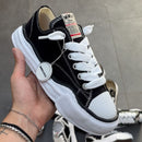 Close-up van de Mihara Yasuhiro Peterson OG Sole sneaker in iemands hand, detail van ruwe canvas textuur