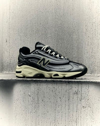 New Balance 1000 Silver Metallic M1000SM in hand met glimmende overlays, technische panelen en futuristisch silhouet

