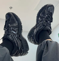 In-hand view van de New Balance 1906A Black. De triple black uitvoering maakt deze sneaker ideaal voor een strakke, tijdloze look – geliefd bij techwear en minimalistische stijlen.

