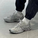 In-hand view van de New Balance 1906A Concrete Silver Metallic. De combinatie van matte en glanzende materialen zorgt voor een futuristische, maar draagbare sneakerrelease.

