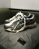 In-hand view van de New Balance 1906A in Olive Juice en Sea Salt. De aardse kleuren en functionele esthetiek maken deze release perfect voor liefhebbers van subtiele maar uitgesproken sneakers.

