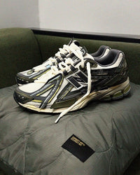 In-hand view van de New Balance 1906A in Olive Juice en Sea Salt. De aardse kleuren en functionele esthetiek maken deze release perfect voor liefhebbers van subtiele maar uitgesproken sneakers.

