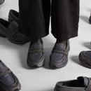 In-hand view van de New Balance 1906L in Magnet kleurstelling. De subtiele glans en het donkere palet maken dit tot een veelzijdige en tijdloze lifestyle runner.

