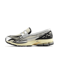 Zijaanzicht van de New Balance 1906L in Silver Metallic en Cream tinten. De combinatie van glanzend zilver en zachte beige tonen geeft deze runner een futuristische maar verfijnde uitstraling.

