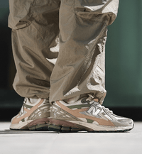 In-hand view van de New Balance M1906NE in Linen en Dark Olivine. De combinatie van zachte tinten en performance-elementen maakt dit model tot een opvallende release binnen de 1906-serie.

