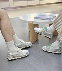 Twee paar New Balance 204L sneakers gedragen op straat naast koffiebeker, gericht op visuele zoekopdrachten rond urban looks en matching outfits