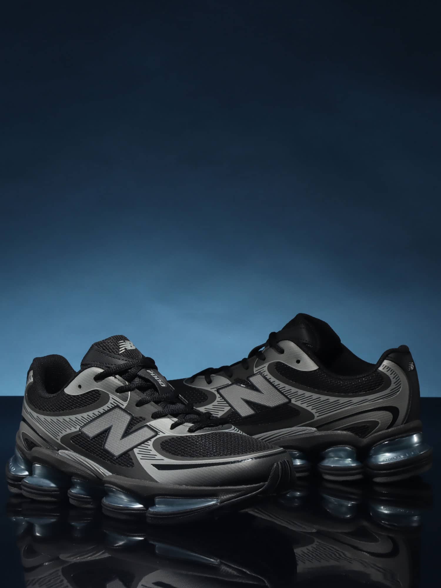 Detail van New Balance ABZORB 2000 Black/Grey – close‑up van mesh textuur, gradient grijze overlays en metallic N‑logo